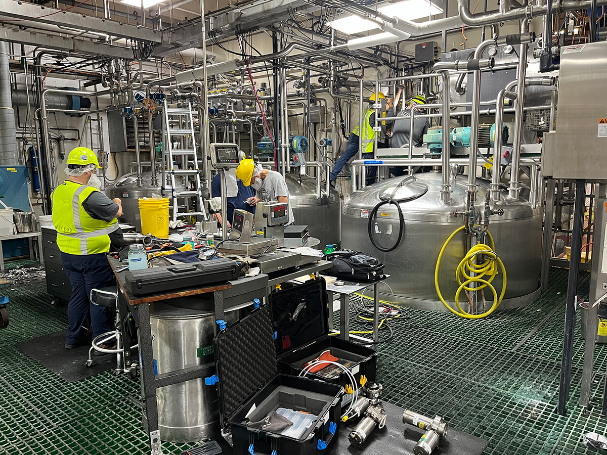 People working in a beverage plant doing maintenance.