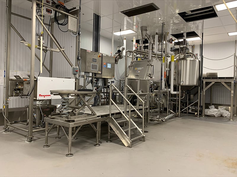 A dry ingredient makedown system with powder blending for food and beverage applications is pictured in a manufacturing facility. 
